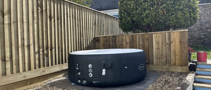 A hot tub surrounded by featheredge fence of varying heights